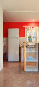 a kitchen with a white refrigerator and red walls at Loicas en El Chaltén - Cabaña in El Chalten +8 photos
