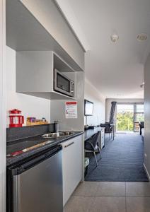 a kitchen with a sink and a microwave at Pukekura Motor Lodge in New Plymouth