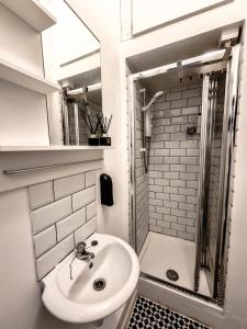 a white bathroom with a sink and a shower at Whole Stylish Apartment 1880s Guinness Worker House in Dublin