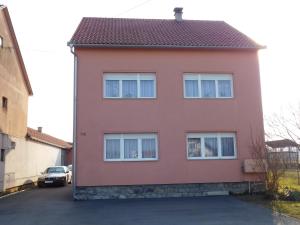 a red house with white windows in a parking lot at Apartman Braja in Virovitica