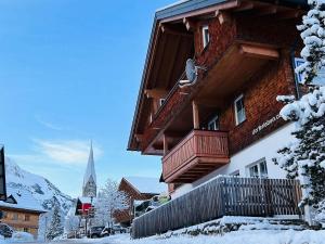 een gebouw met een balkon in de sneeuw bij Dorf(er)leben Ferienwohnung im Kleinwalsertal in Mittelberg