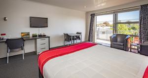 a hotel room with a bed and a desk and a window at Pukekura Motor Lodge in New Plymouth
