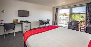 Cette chambre comprend un lit, un bureau et une fenêtre. dans l'établissement Pukekura Motor Lodge, à New Plymouth