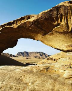 an arch in the desert with mountains in the background at Maraheb Luxury camp in Wadi Rum