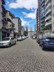 een geplaveide straat met auto's in een stad bij kitnet Guilhermina PG in Praia Grande