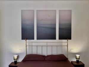 a bedroom with three pictures above a bed at [Piazza Vittoria] Historic Netflix penthouse in Brescia