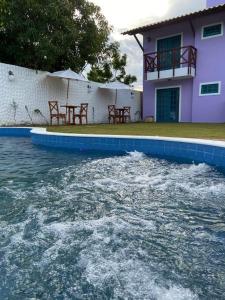 a pool of water with tables and a house at Amoreira Pousada em Barra Grande Piaui in Barra Grande