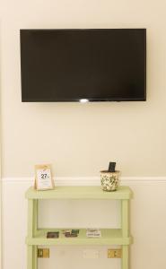 a flat screen tv on a wall with a green table at La Volta in Manduria