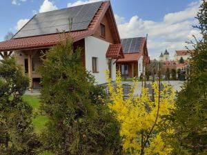 uma casa com painéis solares no telhado em Przystanek Tykocin - domki gościnne w sercu Podlasia em Tykocin