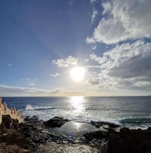 a view of the ocean with the sun in the sky at La Casita de la Charca in Melenara