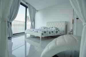 a white bedroom with a bed and a large window at VILA MOLET KOPER in Koper