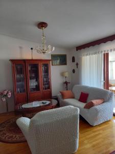 sala de estar con 2 sillas y lámpara de araña en Apartments Raos en Stobreč