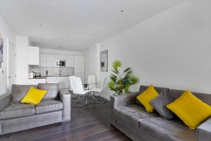 SPACIOUS, BRIGHT & Modern 1 & 2 bed Apartments at Sligo House - CENTRAL Watford في واتفورد: غرفة معيشة مع كنبتين رماديتين ووسائد صفراء