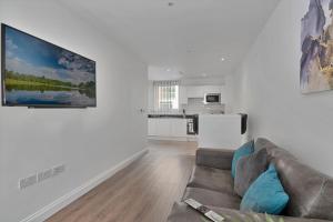 SPACIOUS, BRIGHT & Modern 1 & 2 bed Apartments at Sligo House - CENTRAL Watford في واتفورد: غرفة معيشة مع أريكة ومطبخ