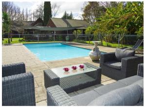 a swimming pool with two wicker chairs and a table at La Frontiere Boutique Accommodation in Gisborne