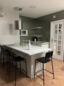 een keuken met een groot wit eiland met zwarte stoelen bij LOFT LA LUNA in Villanueva del Arzobispo