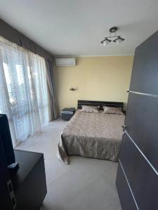 een slaapkamer met een bed en een groot raam bij Apart-Hotel Argo in Lozenets