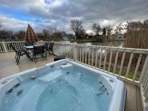 a hot tub on a deck with a table and chairs at Luxury Lakeside Lodge L2 with Hot tub situated at Tattershall Lakes Country Park in Tattershall