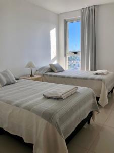 two beds sitting in a room with a window at Güemes Premium, 2 dorm con Vista a las Sierras ALOHA #2 in Córdoba