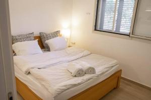 a large white bed with two towels on it at Charming unit in Dead Sea in Ovnat