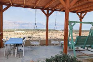 weranda z krzesłami, stołem i huśtawkami w obiekcie Charming unit in Dead Sea w mieście Ovnat