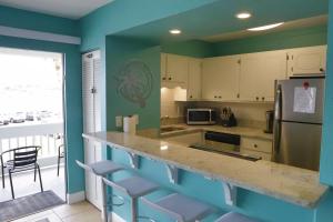 a kitchen with a counter with chairs and a refrigerator at Lazy Palm Heart Of Destin Spring Break Family Beach Vacation! in Destin