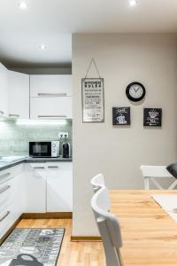 a kitchen with white cabinets and a clock on the wall at Old Town Apartment Podtatranskeho in Košice