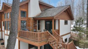 a log cabin with a deck and a tree at 728 Disciples Village Condo in Boyne Falls