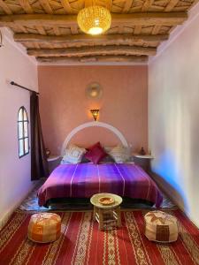 a bedroom with a purple bed and a table at Auberge Tissadrine in Akhendachou nʼAït Ouffi