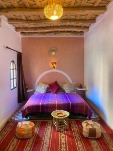 a bedroom with a purple bed and a table at Auberge Tissadrine in Akhendachou nʼAït Ouffi