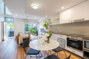 a kitchen and living room with a table and chairs at Swell Byron Bay - Opposite the Belongil Beach in Byron Bay
