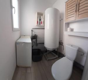 a white bathroom with a toilet and a sink at Gîte La Terrasse in Couffoulens