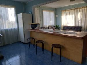 a kitchen with three stools at a counter with a refrigerator at linda casa de campo in Futrono