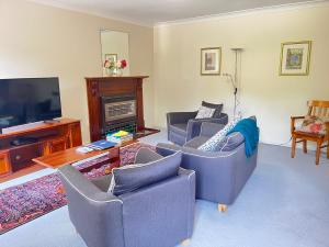 a living room with two couches and a television at Tahara Cottage in Deloraine