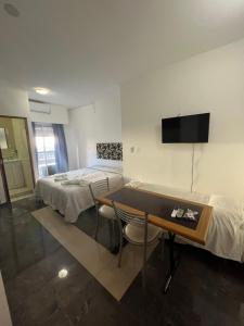 a room with two beds and a table and a tv at DERC Temporarios in Río Cuarto