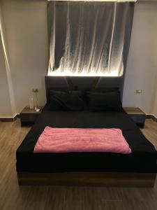 Un dormitorio con una cama negra con una manta rosa. en New Cairo lux apt in lux villa basement1 en El Cairo