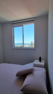 a bedroom with a bed and a window at Apê Encantador em Piçarras in Piçarras