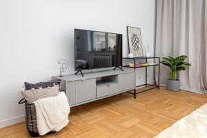 a living room with a television on a cabinet at Spacious Apartment with Swimming Pool, Gym and Sauna WWA40 in Warsaw
