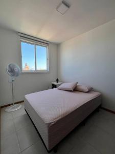 a bedroom with a bed with a fan and a window at Apê Encantador em Piçarras in Piçarras