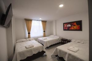 Habitación de hotel con 2 camas y TV en HYG Hotel en Pasto