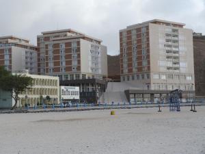 einen Strand mit einigen hohen Gebäuden und einem Spielplatz in der Unterkunft Complexo Multiuso Copacabana in Mindelo