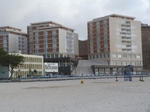 uma praia com alguns edifícios altos e um parque infantil em Complexo Multiuso Copacabana em Mindelo