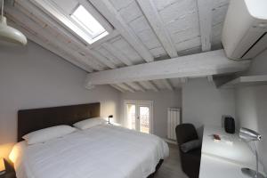 Un dormitorio con una gran cama blanca y una ventana en Loggia del Tenore Suite, en Módena