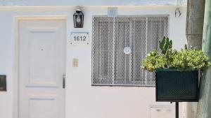 una casa blanca con una puerta con una maceta en El Refugio departamento 2 en Luján