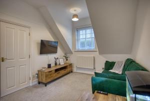 a living room with a green couch and a flat screen tv at 1 or 2 bed in Folkestones West End in Folkestone