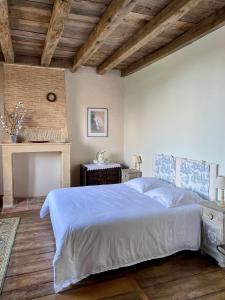 a bedroom with a large white bed and a fireplace at "La Maison de Villars" au coeur de la nature in Pressac