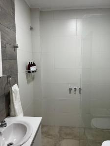 baño blanco con ducha y lavamanos en Departamento Hilario en San Rafael