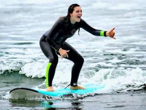 a woman riding a wave on a surfboard in the water at Tigmi surf morocco in Tiguemmi nʼAït Bihi