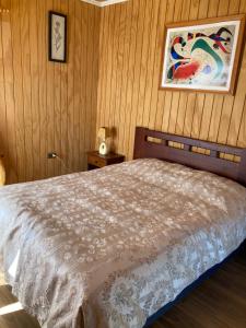 1 dormitorio con 1 cama y una pintura en la pared en Cabaña En Lago colbun, sector Pasó Nevado, en Talca