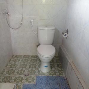 La salle de bains est pourvue d'une douche et de toilettes blanches. dans l'établissement Bali Livin,tayehomestay, à Banjarangkan